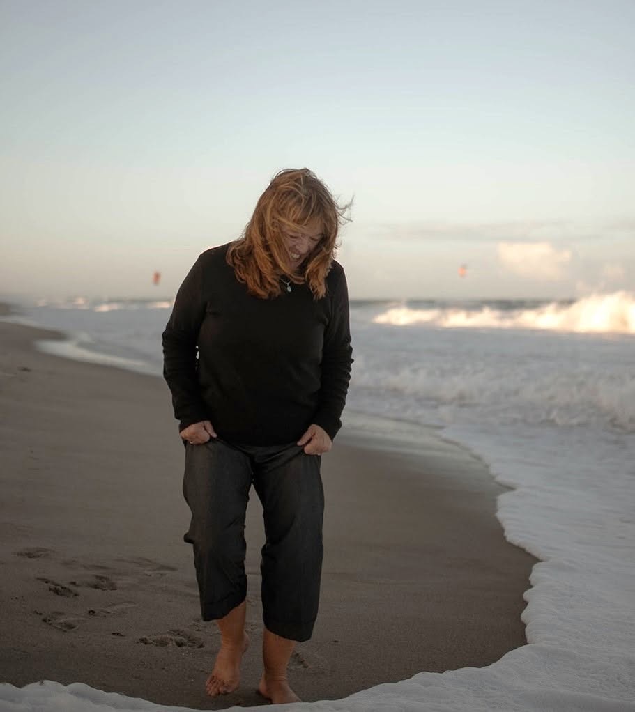 Lynda walking barefoot along the surf